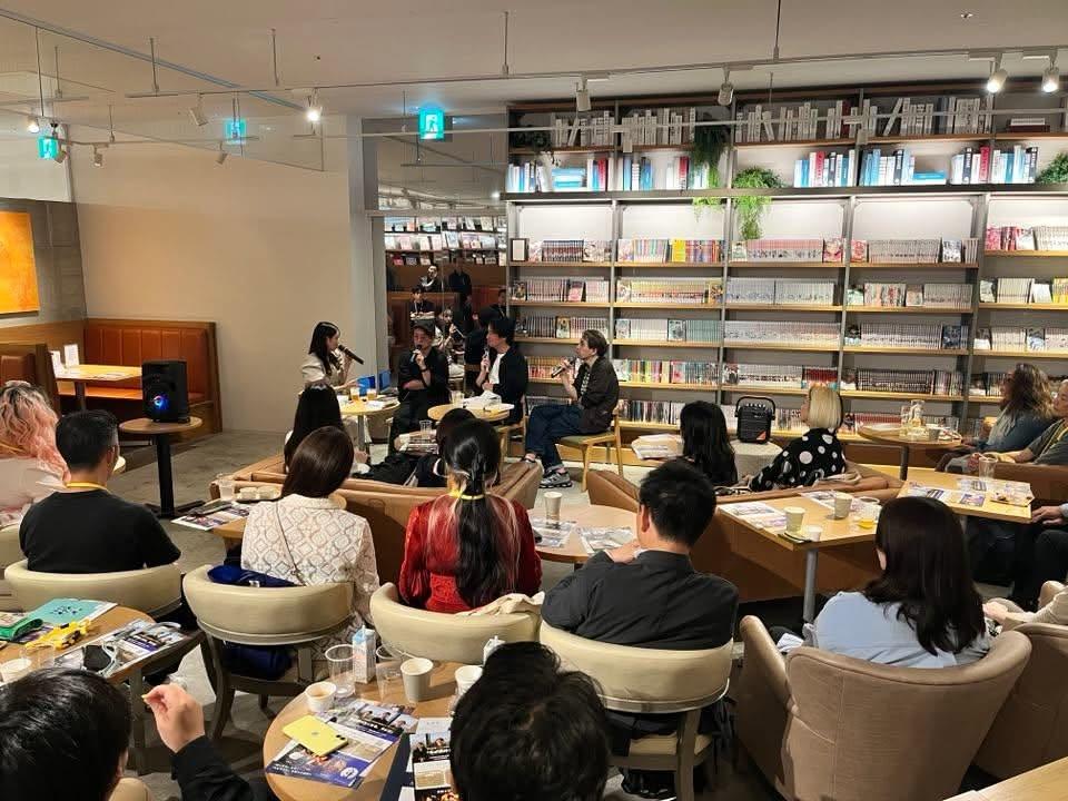 テーブル席の参加者の前で話す登壇者たち。背後に書棚が並ぶSHARE LOUNGEの会場全景